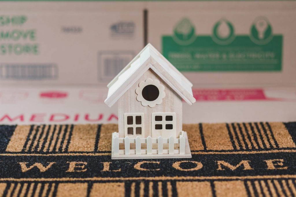 A model of a house positioned on a doormat.