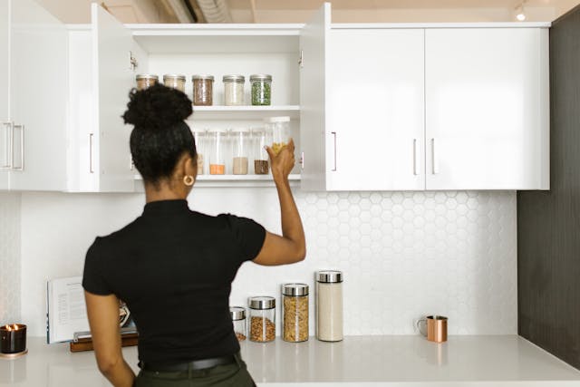 woman putting spices in her kitchen storage